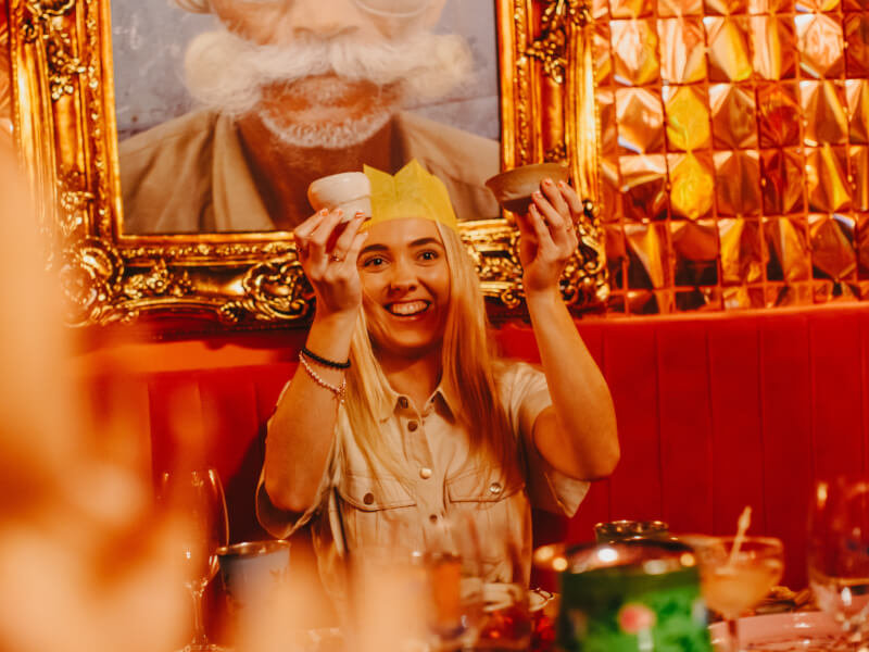 Smiling girl in gold-coloured room, holding up two clay vessels